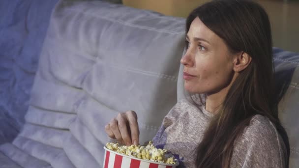Dojrzałe kobiety jedzenie popcorn, uśmiechając się do kina z bliska - Materiał filmowy, wideo