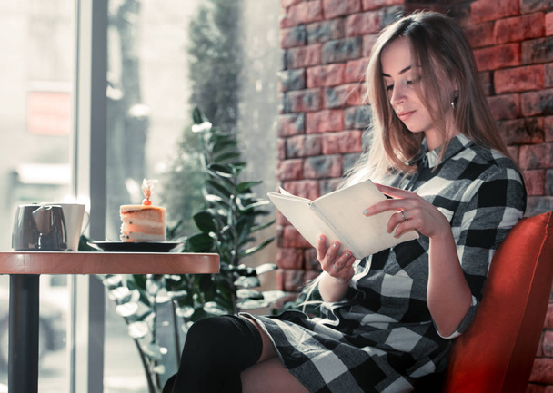 Όμορφο κορίτσι διαβάζει ένα βιβλίο σε ένα καφέ - Φωτογραφία, εικόνα