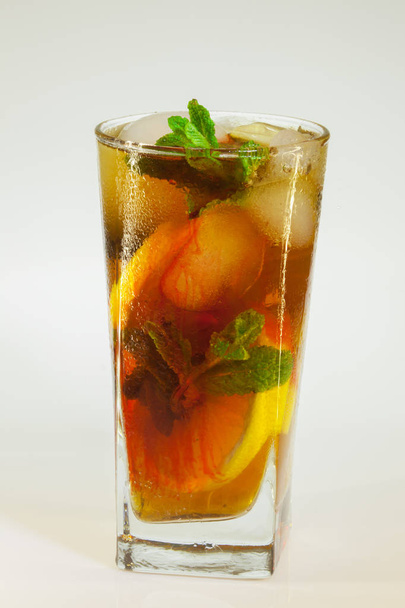 druppels rose op een glas koud drankje met ijs, citroen en munt op een witte achtergrond - Foto, afbeelding