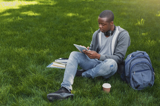 Estudante afro-americano na grama com tablet oudoors
 - Foto, Imagem