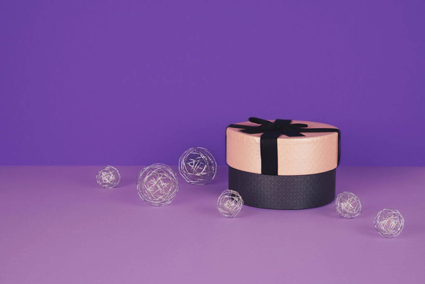 Pink gift box with ribbon on an ultraviolet background. - Фото, зображення