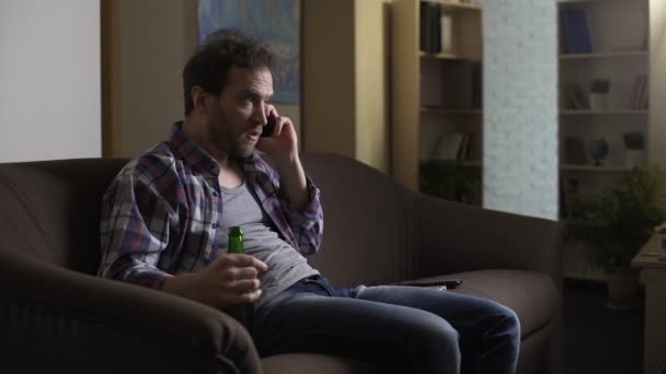 Messy guy arguing over mobile phone, drinking beer from bottle, frustration - Felvétel, videó