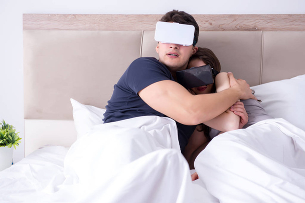 Wife and husband with virtual reality goggles in the bed - 写真・画像