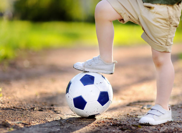 Little boy having fun playing a soccer/football game on summer day - 写真・画像