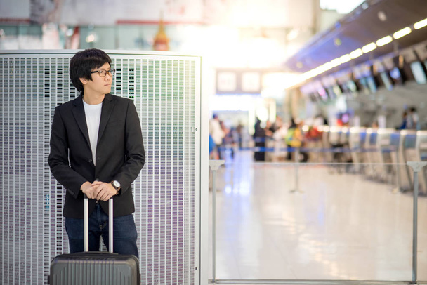 Jeune homme asiatique avec des bagages dans le terminal de l'aéroport
 - Photo, image