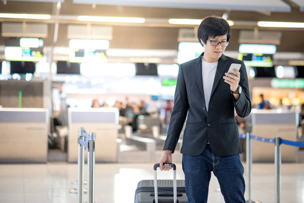Młody człowiek azjatyckich za pomocą smartfona w terminalu lotniska - Zdjęcie, obraz