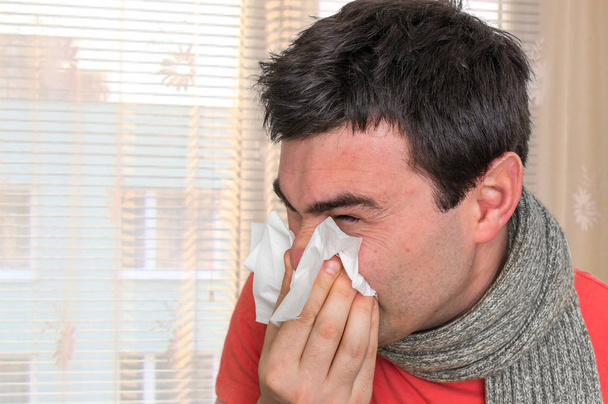 Больной человек с гриппом или холодный чихание в носовой платок
 - Фото, изображение