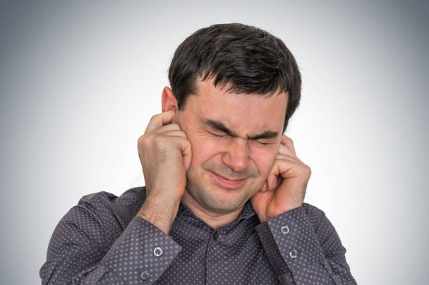 Homem cobrindo seus ouvidos para proteger do barulho alto
 - Foto, Imagem