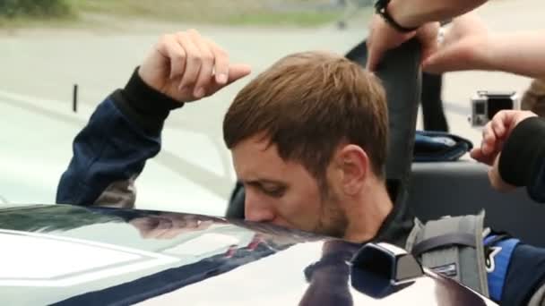 Male sitting in sports car, crew member fastening seat belts, racing competition - Materiał filmowy, wideo