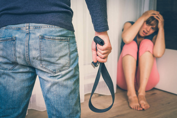 Hombre con cinturón golpeando a su esposa - violencia doméstica
 - Foto, Imagen