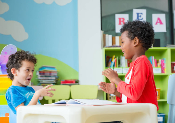 Two boy kid sit on table and coloring in book  in preschool library,Kindergarten school education concept. - Fotó, kép