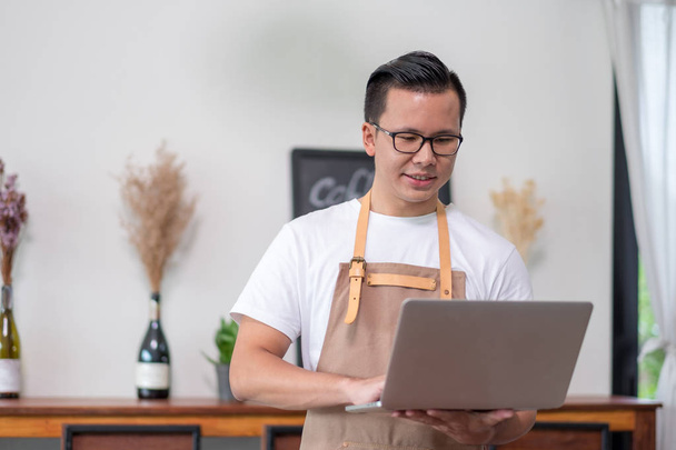Asian male Barista cafe owner using laptop checking stock busine - Foto, immagini