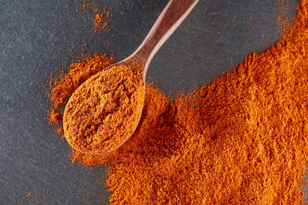 Texture background. Red chilli pepper powder mixed with wooden spoon. Top view - Photo, image