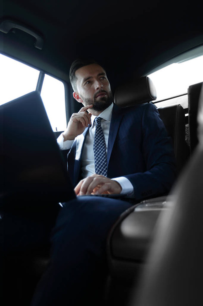 businessman working with laptop and looking out the window of a car - Foto, imagen