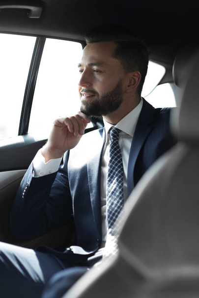 Smiling business man sitting in the back seat of a car - Foto, Imagem