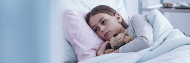 Sick girl hugging plush toy - Foto, afbeelding