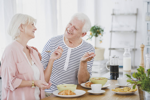 Smiling senior couple eating croissants - 写真・画像