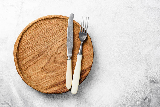 Vintage silverware and wooden plate on grey concrete background - Foto, imagen