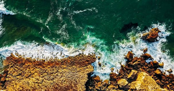 Luchtfoto van vliegende Drone van oceaan golven drukproef op rotsachtige strand landschap - Foto, afbeelding