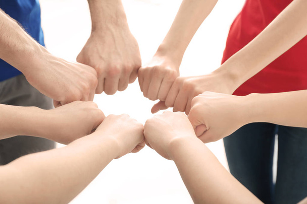 Young people putting hands together on light background. Unity concept - Фото, зображення