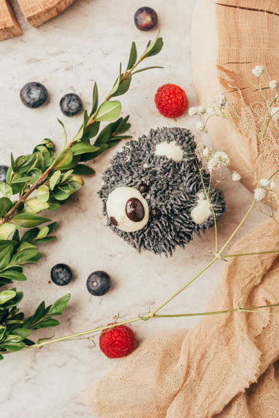 top view of sweet tasty muffin in shape of bear and fresh berries with green branch - Φωτογραφία, εικόνα