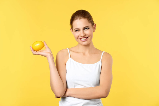 Beautiful young woman with ripe lemon on color background - Foto, immagini