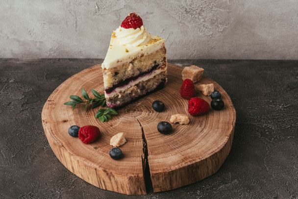 vista de cerca de pastel sabroso dulce con crema batida y bayas en el tablero de madera
 - Foto, Imagen