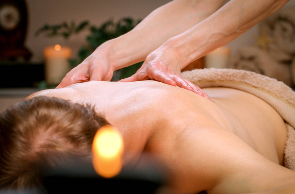 Massage therapeut masseren schouders en rug van een man - Foto, afbeelding