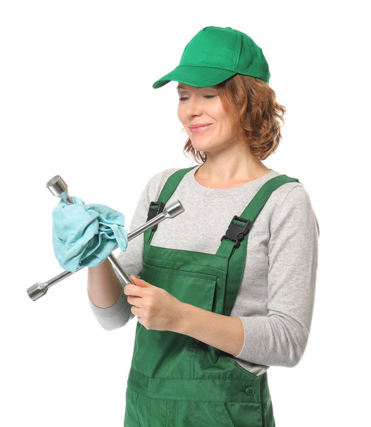 Female auto mechanic wiping lug wrench with rag on white background - Valokuva, kuva