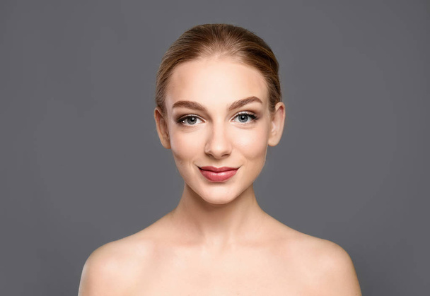 Portrait of beautiful young woman with clear skin on grey background - Фото, зображення