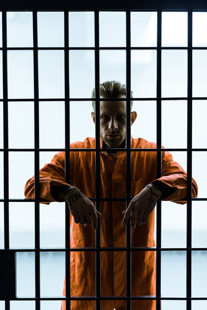 prisionero poniendo las manos entre rejas de la prisión y mirando la cámara
 - Foto, imagen