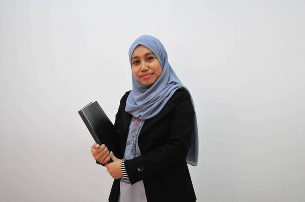 Молодая мусульманская предпринимательница держит в руках книгу отчетов
 - Фото, изображение