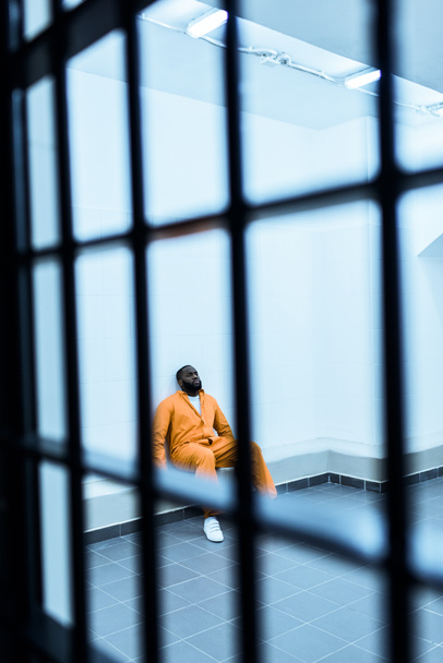 Afrikkalainen amerikkalainen vanki istuu penkillä sellissä.
 - Valokuva, kuva
