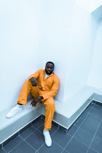 μεγάλη γωνία προβολής Αφρικανικός Αμερικανός κρατούμενος που κάθεται στον πάγκο - Φωτογραφία, εικόνα