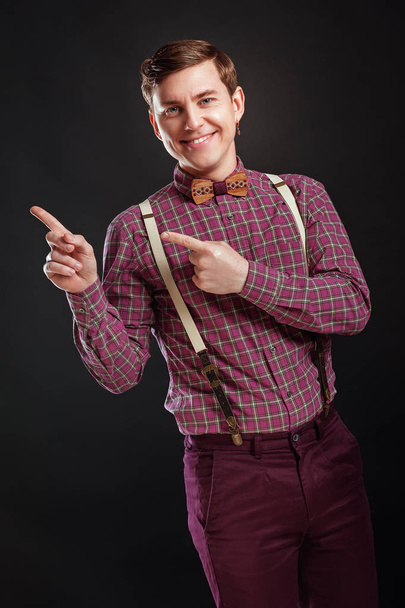 Olha para isto! Bonito jovem homem científico em gravata de arco de camisa vintage apontando espaço de cópia e sorrindo enquanto estava contra fundo preto. Educação Emotios Pessoas Conceitos de negócios
 - Foto, Imagem