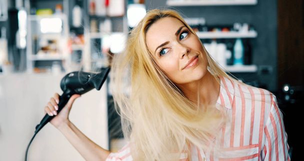 Close up portrait of beautiful young woman drying hairstyle - Valokuva, kuva