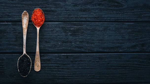 Spoon with black and red caviar on a wooden background. Top view. Free space for text. - Фото, зображення