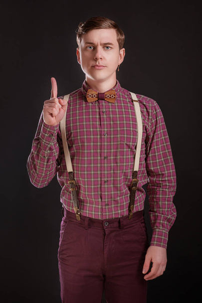 Attention! Strict Handsome young man in vintage shirt bow tie keeping finger raised and looking at camera while standing against black or grey background. People Emotions Fashion Businness Education - Photo, Image