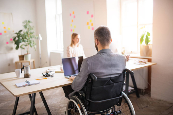 Two business people with wheelchair in the office. - 写真・画像