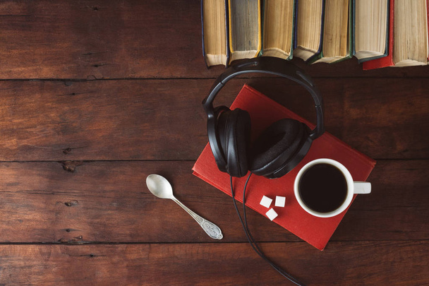 Βιβλία, μαύρα ακουστικά, κύβους ζάχαρης και λευκού Κύπελλο με ζεστό καφέ - Φωτογραφία, εικόνα