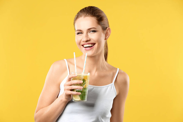 Beautiful young woman with glass of lemonade on color background - Foto, imagen