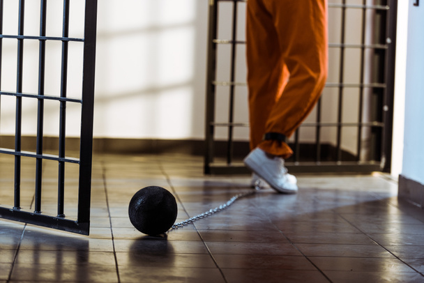 immagine ritagliata del prigioniero che cammina in uniforme arancione con peso legato alla gamba
 - Foto, immagini
