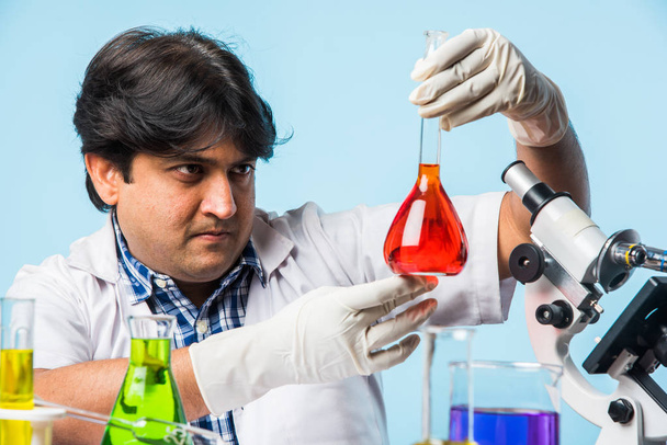Azjatyckie/Indian Mężczyzna naukowiec lub lekarza lub nauka student eksperymentować z mikroskopem, chemikalia, laptop i smartfon w laboratorium - Zdjęcie, obraz