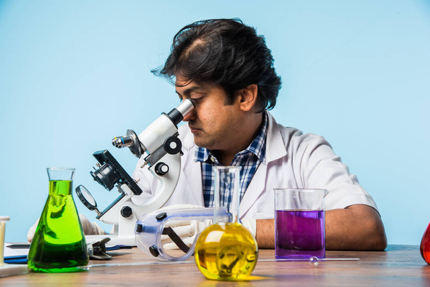 Asya/Hindistan erkek bilim adamı veya doktor ya da bilim öğrenci mikroskop ve kimyasallar, dizüstü bilgisayar ve smartphone bir laboratuvarda deneme - Fotoğraf, Görsel