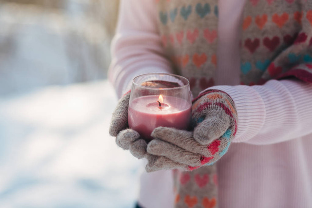 Young girl holds candle in hands in winter park - Photo, image