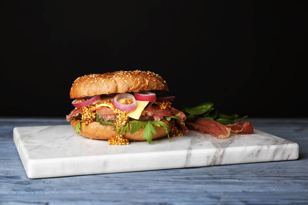Tasty burger on marble board against dark background - Фото, зображення