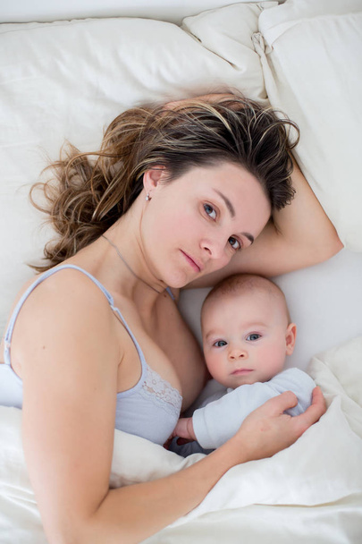 Young mother breastfeeds her baby, holding him in her arms and s - Foto, Imagen