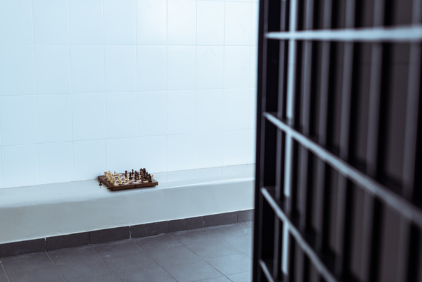 Leere Gefängniszelle mit Schachbrett auf Bank - Foto, Bild