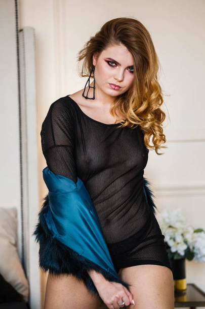 Studio shot of beauty model wearing black blouse and blue coat. Young woman with stylish makeup posing at home  - Фото, зображення