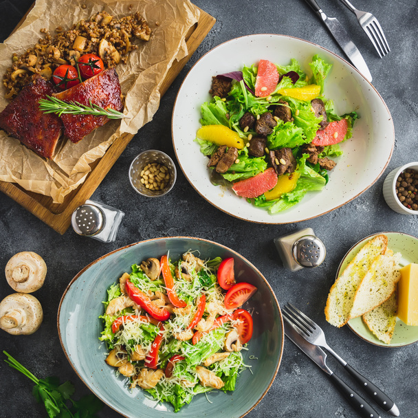 Pohled shora deskami, zeleninové saláty a pečené maso s pohankou na dřevěné desce  - Fotografie, Obrázek